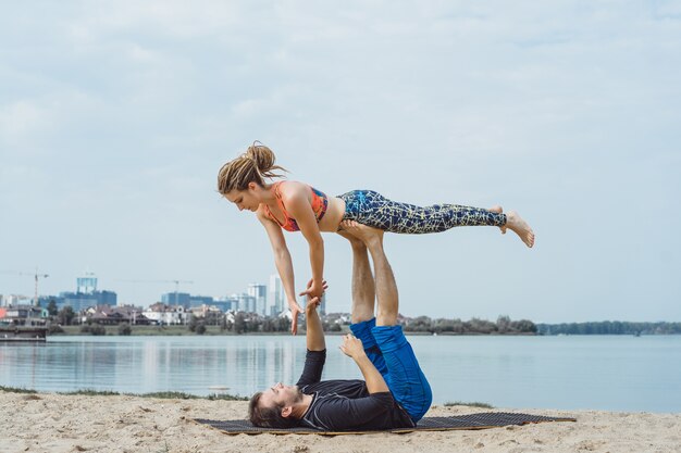 giovane coppia praticare yoga sullo sfondo della città
