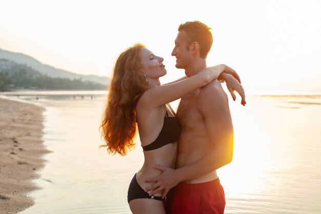 Giovane coppia romantica sexy innamorata felice sulla spiaggia estiva insieme divertendosi indossando costumi da bagno
