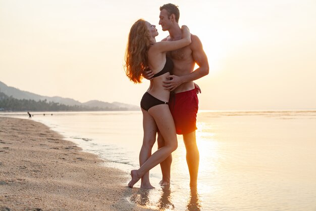 Giovane coppia romantica sexy innamorata felice sulla spiaggia estiva insieme divertendosi indossando costumi da bagno