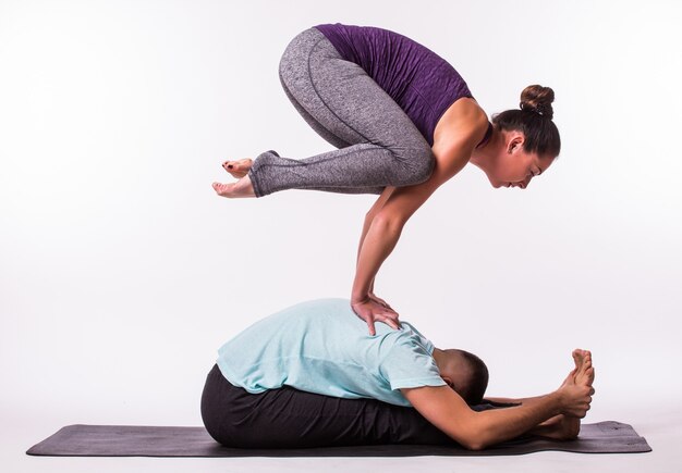 Giovane coppia sana uomo e donna in posizione yoga su sfondo bianco