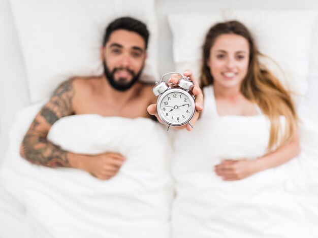 Giovane coppia sdraiata sul letto mostrando sveglia
