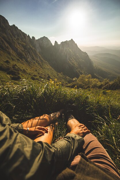 Giovane coppia seduta in cima alla montagna e godersi la vista durante il tramonto