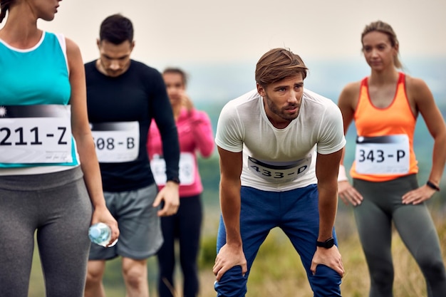 Giovane corridore maschio che si sente esausto dopo aver partecipato a una maratona in natura