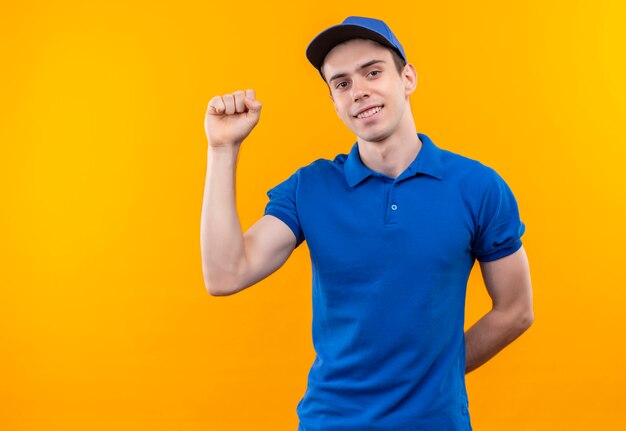 Giovane corriere che indossa l'uniforme blu e cappuccio blu che fa il pugno felice