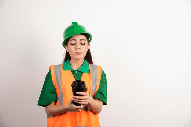 Giovane costruttore femminile che considera tazza nera. Foto di alta qualità