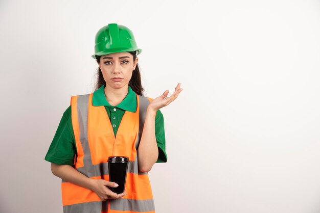 Giovane costruttore femminile che tiene tazza nera. Foto di alta qualità