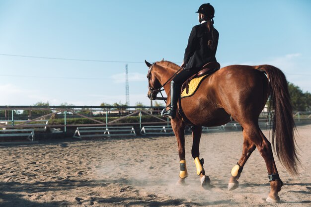 Giovane cowgirl stupefacente che si siede sul cavallo all'aperto