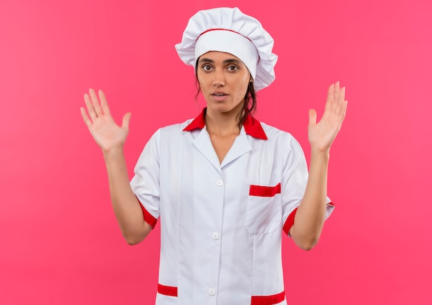 giovane cuoco femminile che indossa l'uniforme dello chef che mostra le dimensioni sul muro rosa isolato con spazio di copia