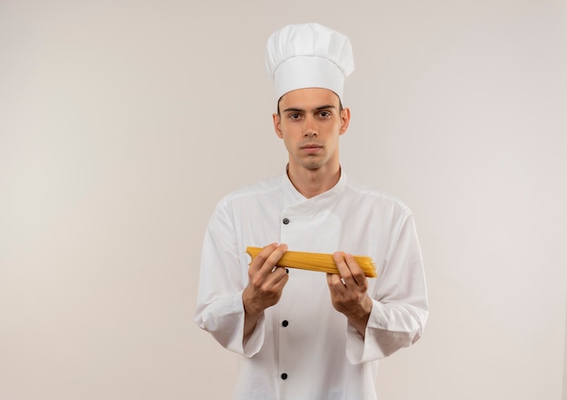 giovane cuoco maschio che indossa l'uniforme dello chef tenendo gli spaghetti sul muro bianco isolato con spazio di copia