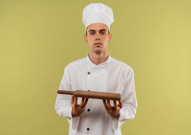 giovane cuoco maschio che indossa uniforme da chef tenendo il tagliere sulla parete verde isolata con spazio di copia