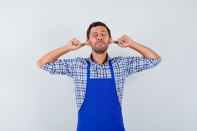 Giovane cuoco maschio in un grembiule blu e una camicia