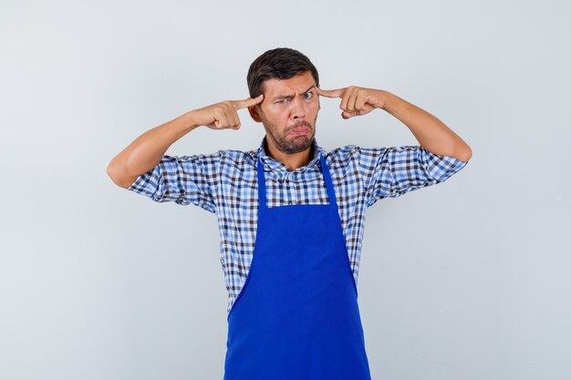 Giovane cuoco maschio in un grembiule blu e una camicia