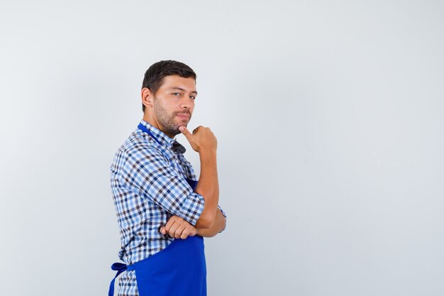 Giovane cuoco maschio in un grembiule blu e una camicia