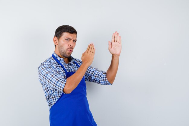 Giovane cuoco maschio in un grembiule blu e una camicia