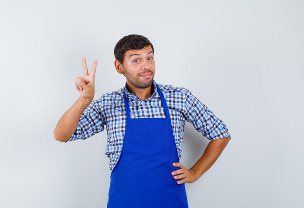 Giovane cuoco maschio in un grembiule blu e una camicia