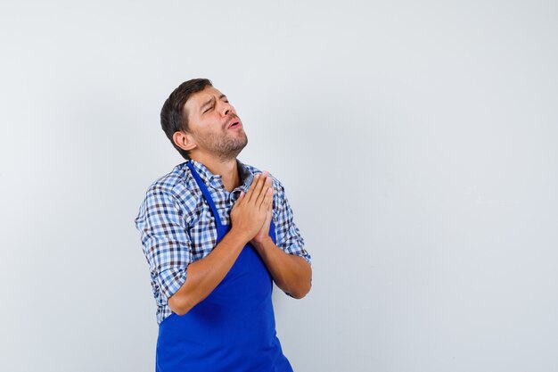 Giovane cuoco maschio in un grembiule blu e una camicia