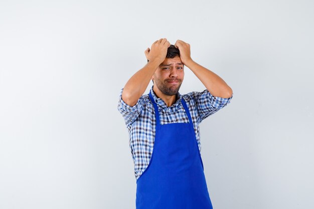 Giovane cuoco maschio in un grembiule blu e una camicia