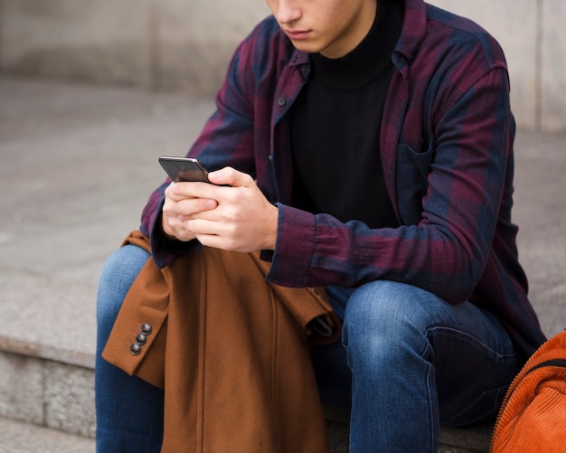 Giovane del primo piano che passa in rassegna il suo telefono