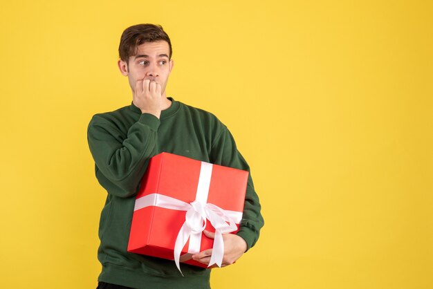 Giovane di vista frontale con il maglione verde che sta sul colore giallo