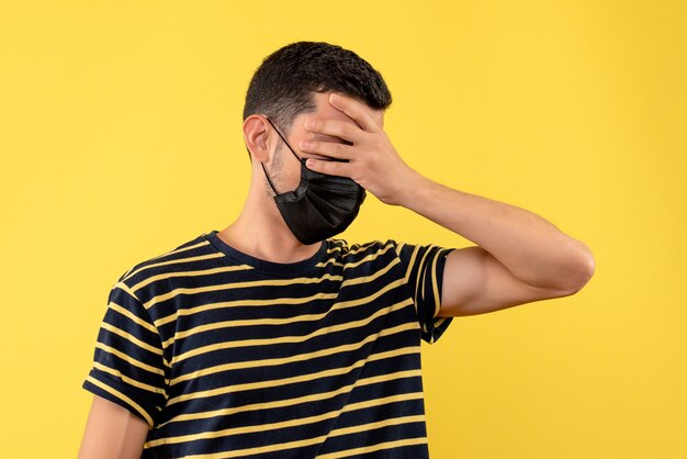 Giovane di vista frontale in maglietta a strisce in bianco e nero che tiene il fondo giallo della testa