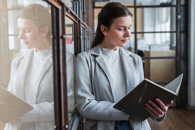 Giovane diario attraente della lettura della donna di affari in ufficio