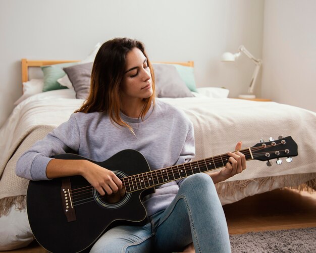 Giovane donna a suonare la chitarra a casa