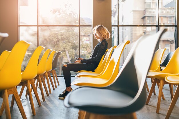 Giovane donna abbastanza impegnata seduta da sola nella sala conferenze