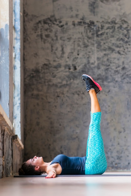 Giovane donna adatta che fa allungando esercizio sulla stuoia di yoga