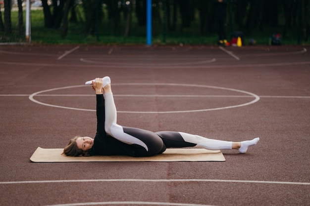 Giovane donna adatta in abiti sportivi si allena all'aperto nel parco giochi.