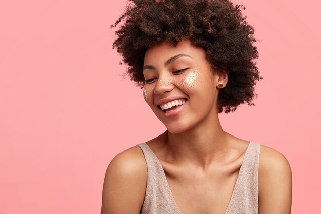 Giovane donna afro-americana con glitter sul viso