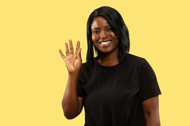 Giovane donna afro-americana isolata su spazio giallo, espressione facciale. Bellissimo ritratto femminile a mezzo busto.