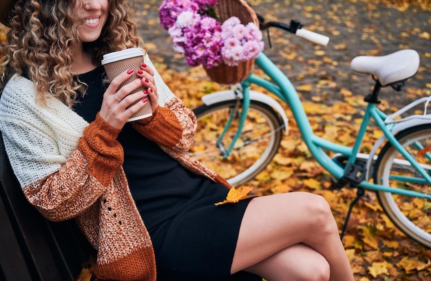 Giovane donna alla moda che beve caffè per strada