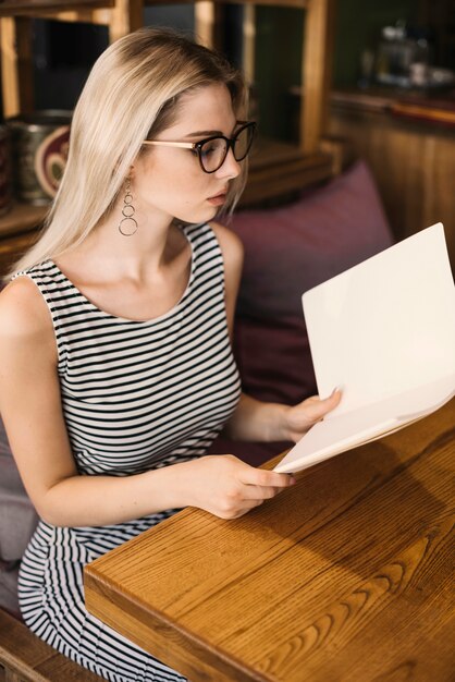 Giovane donna alla moda che controlla i menu nel ristorante