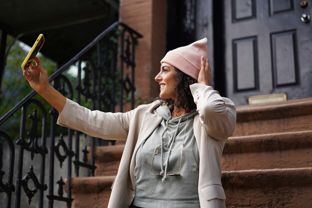 Giovane donna alla moda che prende selfie mentre esplora la città