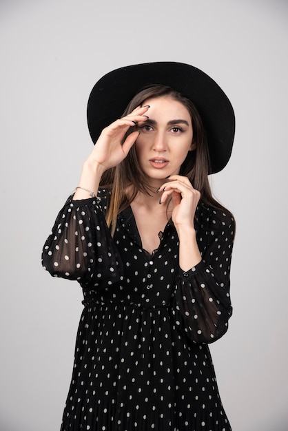 Giovane donna alla moda con cappello nero che sembra così seria.