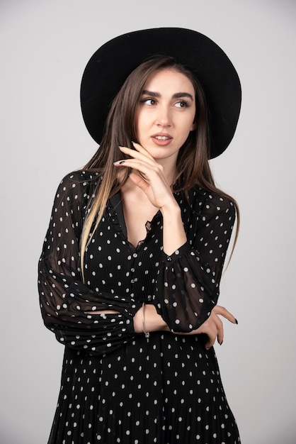 Giovane donna alla moda con il cappello nero che prova a guardare.