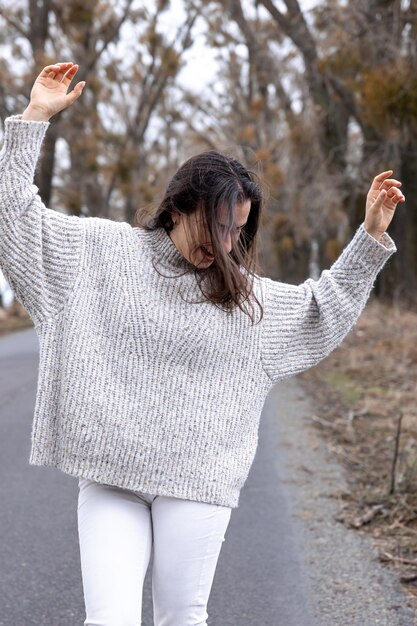 Giovane donna alla moda dalla strada asfaltata nella stagione fredda
