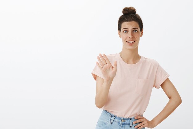 giovane donna alla moda non divertita in posa contro il muro bianco