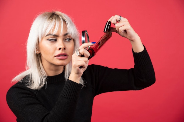 Giovane donna alla ricerca su un nastro fotografico su uno sfondo rosso. Foto di alta qualità