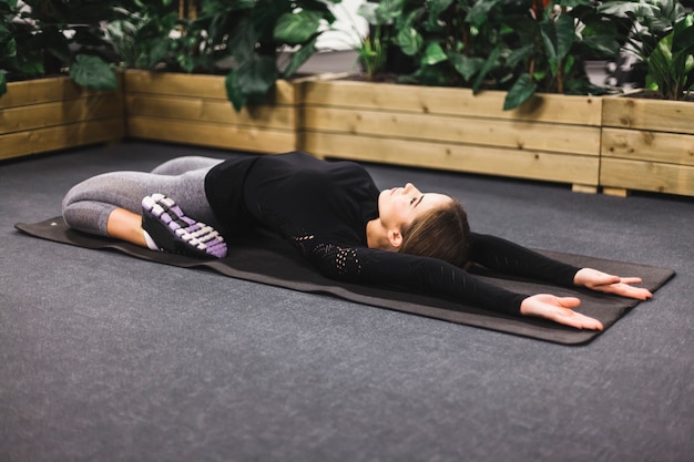 Giovane donna allegra che fa esercitazione sulla stuoia di yoga