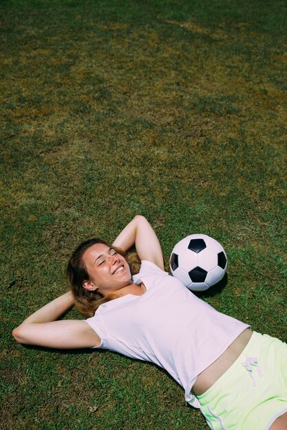 Giovane donna allegra che riposa al campo di calcio