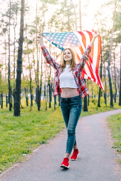 Giovane donna allegra con la bandiera di USA