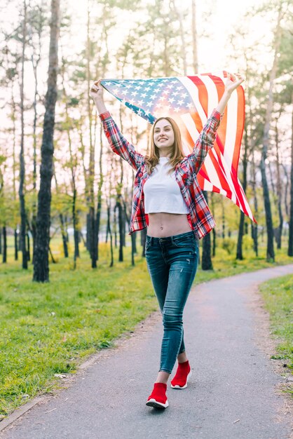 Giovane donna allegra con la bandiera di USA