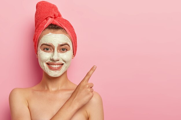 Giovane donna allegra con un sorriso gentile, punta il dito indice