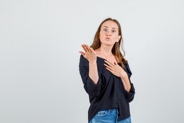 Giovane donna alzando la mano in camicia, pantaloncini e guardando arrabbiato. vista frontale.