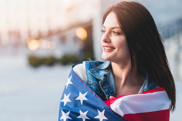 Giovane donna arrotolando in bandiera americana