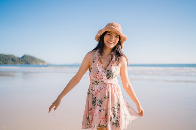 Giovane donna asiatica che cammina sulla spiaggia. La bella femmina felice si distende camminando sulla spiaggia