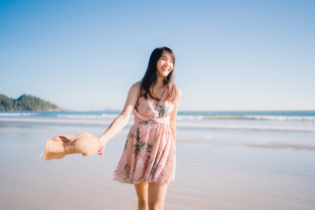 Giovane donna asiatica che cammina sulla spiaggia. La bella femmina felice si distende camminando sulla spiaggia