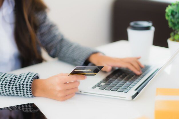 giovane donna asiatica che usando la carta di credito con il computer portatile per lo shopping online