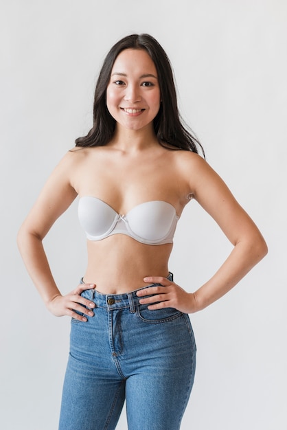 Giovane donna asiatica in reggiseno e jeans